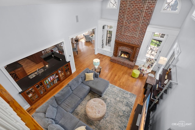 living area with wood finished floors, high vaulted ceiling, a healthy amount of sunlight, and a fireplace