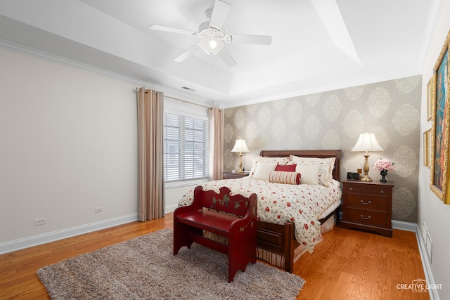 bedroom with baseboards, wallpapered walls, wood finished floors, and a raised ceiling