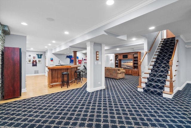 finished basement with stairway, bar, ornamental molding, and baseboards
