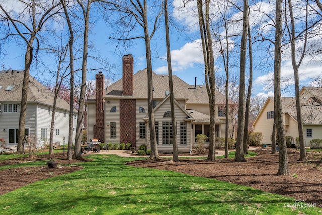 back of house featuring a lawn, a chimney, and a patio area