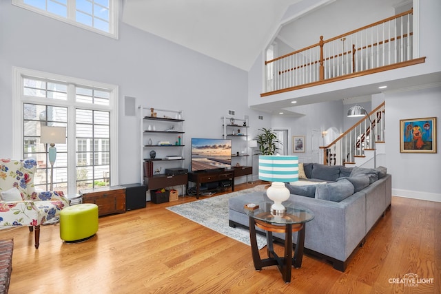 living area featuring baseboards, stairs, wood finished floors, and high vaulted ceiling