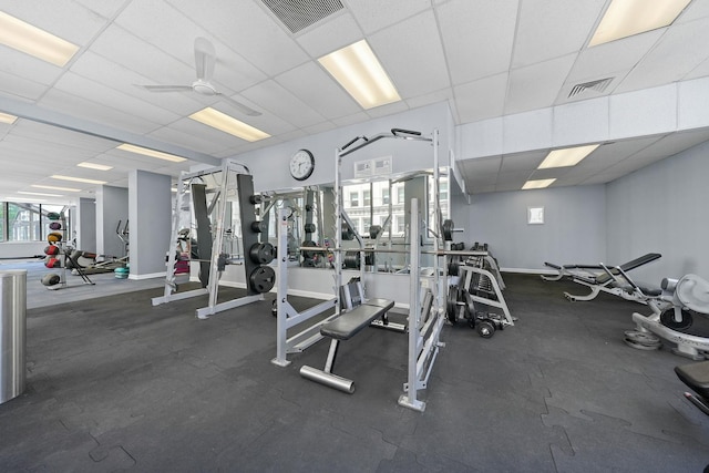 exercise room with visible vents, a ceiling fan, a paneled ceiling, and baseboards