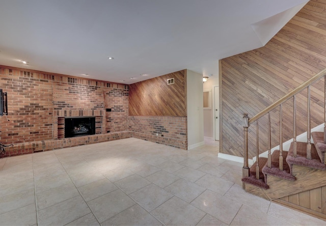 unfurnished living room featuring wooden walls, recessed lighting, and a brick fireplace