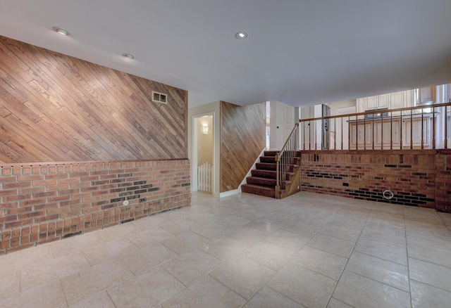 interior space with wooden walls, recessed lighting, stairs, and brick wall