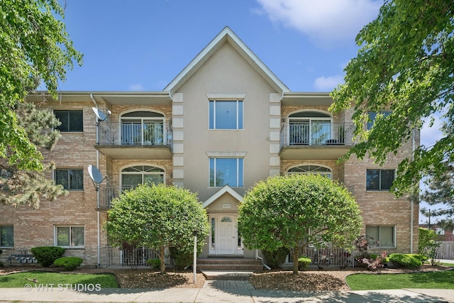 9439 S 79th Ave Unit 102, Hickory Hills, IL 60457 - view of property with a balcony, stucco siding, and brick siding