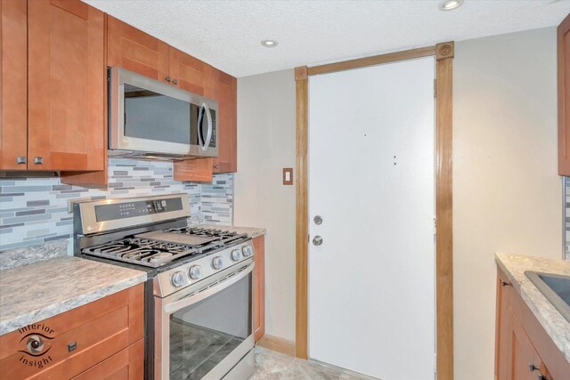 kitchen with stainless steel appliances, tasteful backsplash, light countertops, brown cabinets, and a textured ceiling