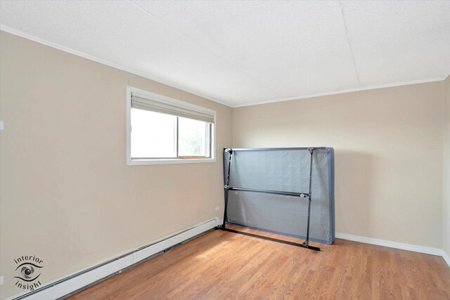unfurnished bedroom featuring a baseboard heating unit, baseboard heating, wood finished floors, a closet, and baseboards