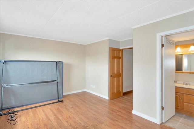 empty room with a baseboard heating unit, crown molding, light wood-type flooring, and baseboards