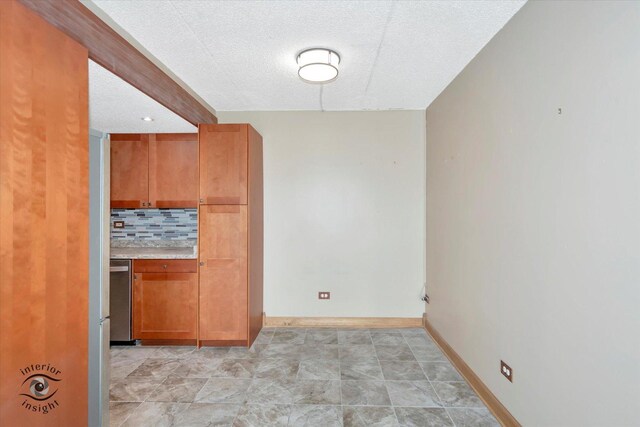 spare room featuring a textured ceiling and baseboards