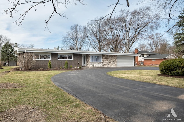single story home featuring driveway, a chimney, a front lawn, and a garage