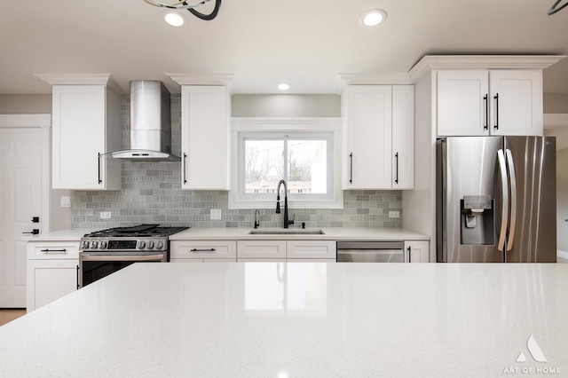 kitchen with light countertops, wall chimney exhaust hood, tasteful backsplash, a sink, and stainless steel appliances