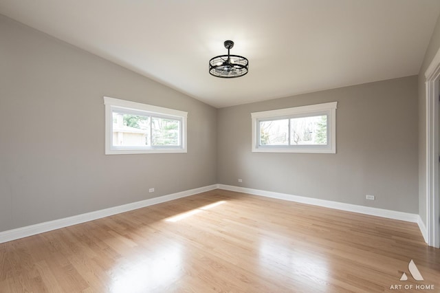 spare room with light wood-style flooring, lofted ceiling, and a healthy amount of sunlight