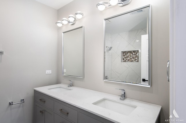 bathroom with double vanity, a sink, and a tile shower