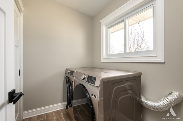 clothes washing area featuring laundry area, washer and clothes dryer, baseboards, and dark wood finished floors