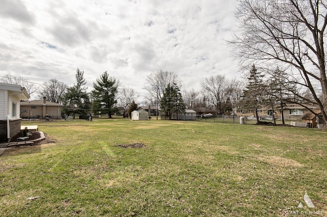 view of yard featuring an outbuilding, fence, and a storage shed