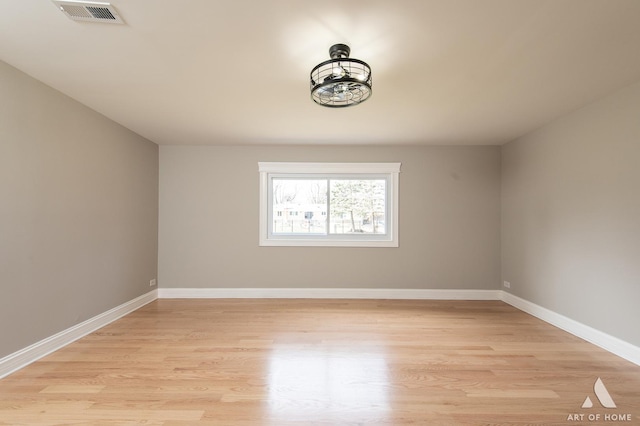spare room featuring baseboards, light wood-type flooring, and visible vents