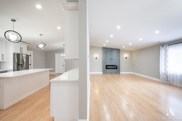 kitchen featuring light countertops, white cabinetry, baseboards, light wood-type flooring, and stainless steel refrigerator with ice dispenser