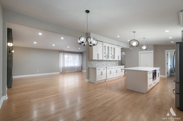 kitchen featuring a kitchen island, glass insert cabinets, recessed lighting, light countertops, and white cabinetry