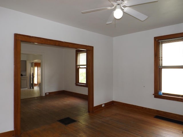 unfurnished room with baseboards, ceiling fan, wood finished floors, and visible vents