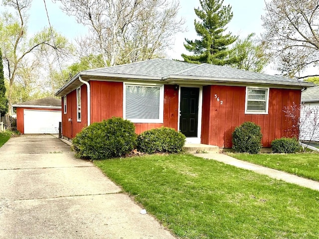 view of front of home with a garage, roof with shingles, an outbuilding, and a front yard