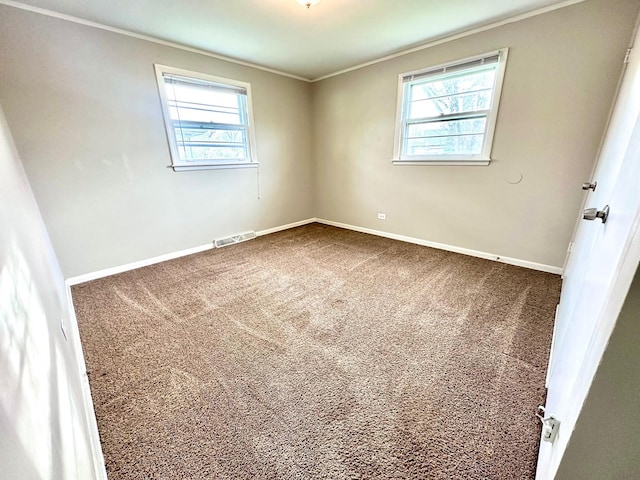 carpeted spare room with visible vents, ornamental molding, baseboards, and a healthy amount of sunlight