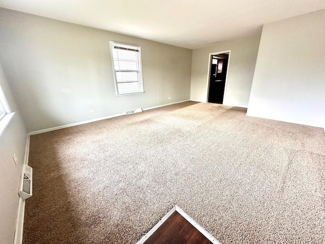 empty room featuring visible vents, baseboards, and dark colored carpet