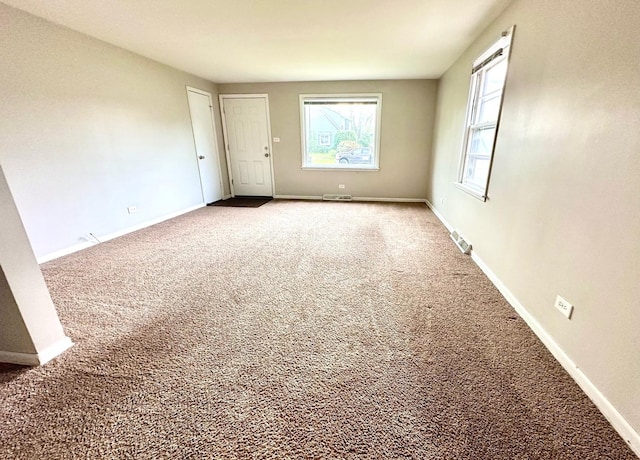 empty room with carpet floors, baseboards, and visible vents