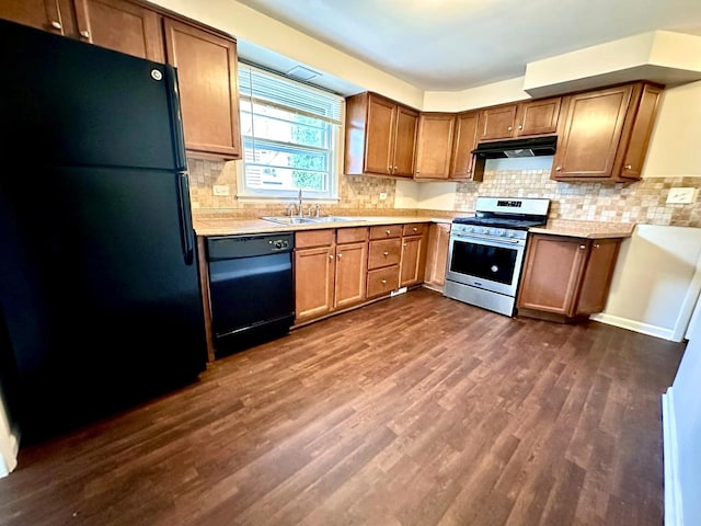 kitchen featuring dark wood-style floors, light countertops, under cabinet range hood, a sink, and black appliances