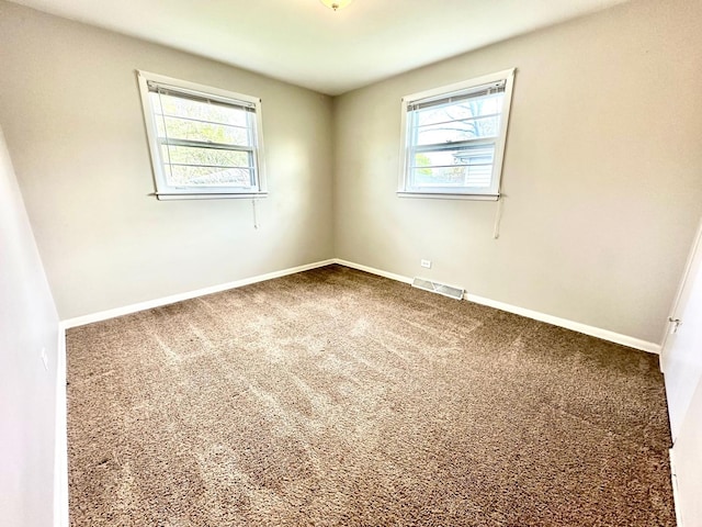 carpeted spare room with visible vents and baseboards