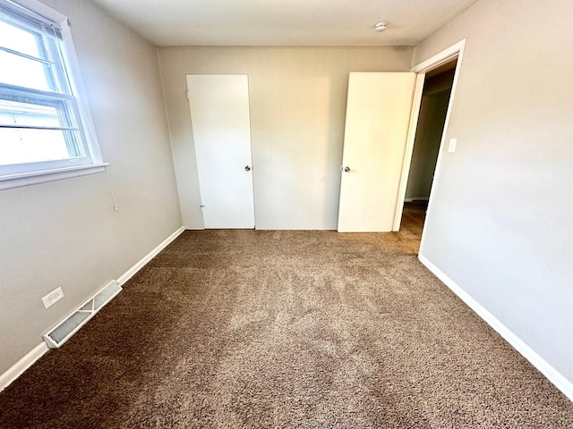 unfurnished bedroom with carpet floors and visible vents