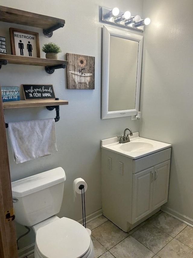 half bathroom with tile patterned flooring, baseboards, toilet, and vanity