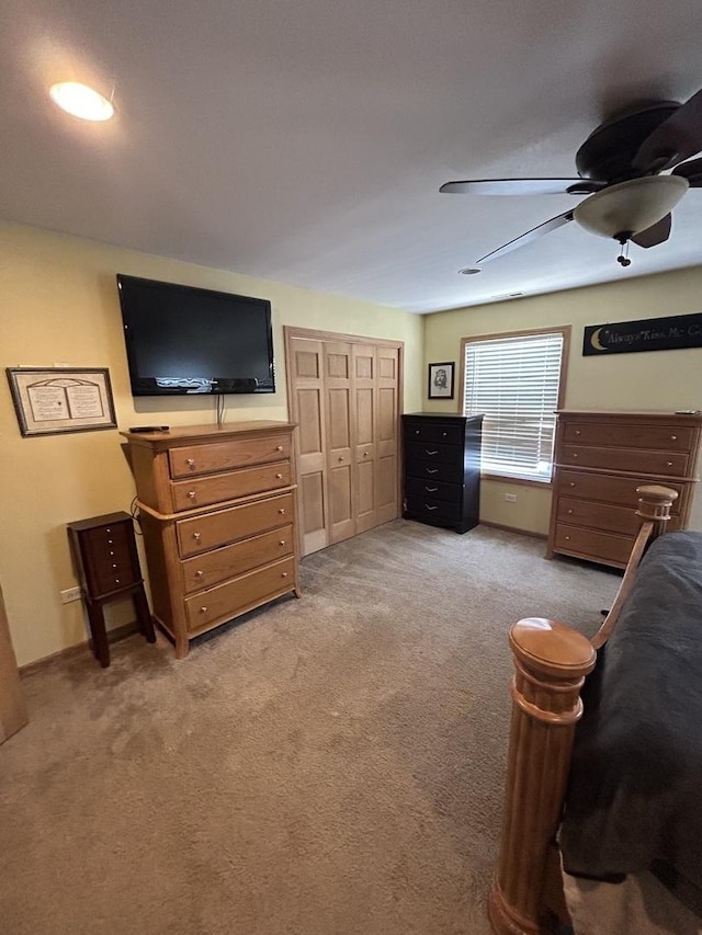 bedroom featuring light colored carpet, a ceiling fan, and a closet