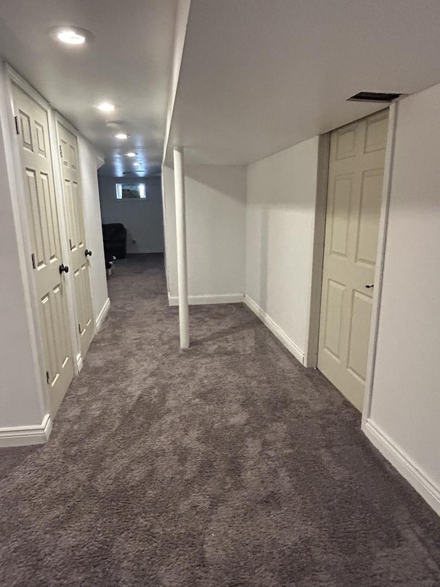 finished below grade area featuring dark carpet and baseboards
