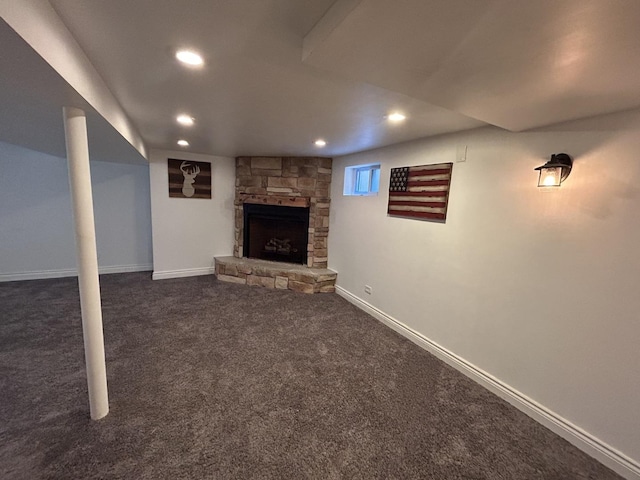 basement featuring dark colored carpet, recessed lighting, baseboards, and a stone fireplace