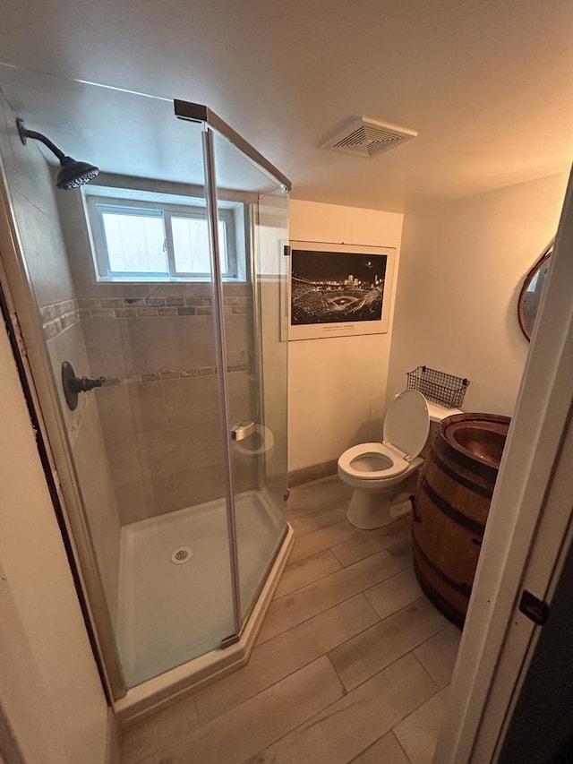 full bathroom with toilet, visible vents, a shower stall, and wood finished floors