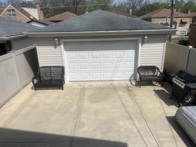 garage with fence and concrete driveway