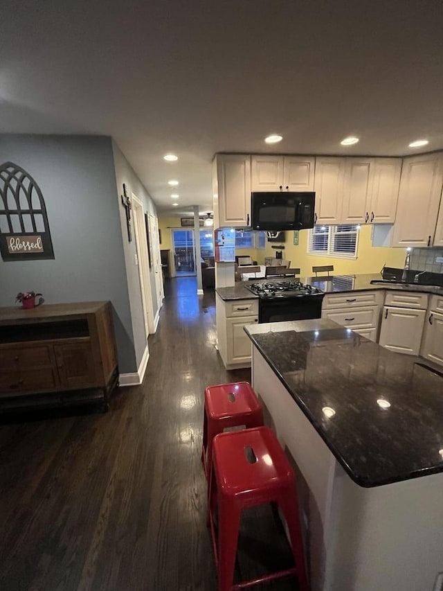 kitchen with recessed lighting, black appliances, dark wood-style floors, and white cabinetry