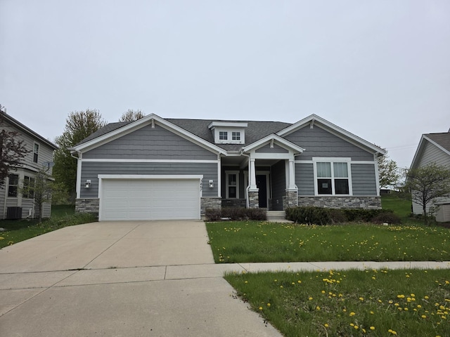 craftsman inspired home featuring an attached garage, a front yard, stone siding, and concrete driveway