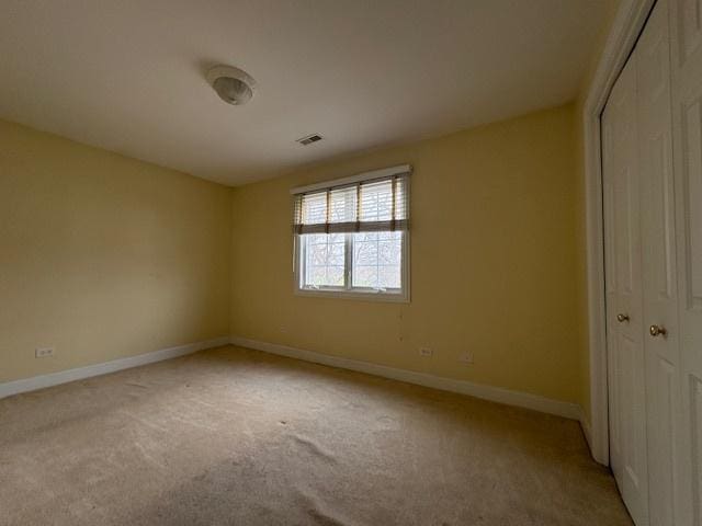 unfurnished bedroom with baseboards, light colored carpet, visible vents, and a closet