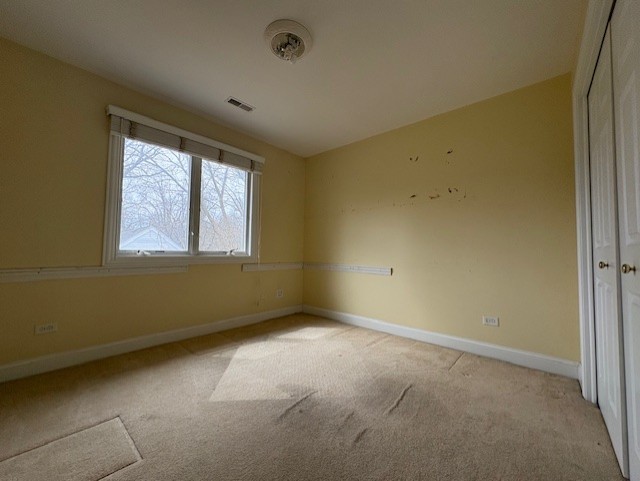 spare room featuring light colored carpet, baseboards, and visible vents