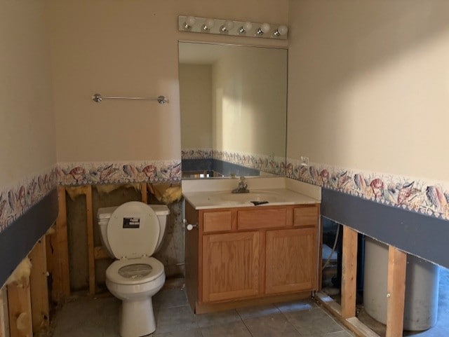 half bathroom with tile patterned flooring, toilet, and vanity