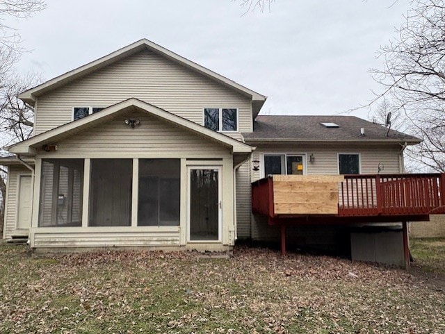 rear view of house featuring a sunroom and a deck
