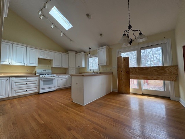 kitchen with gas range gas stove, white cabinetry, a chandelier, rail lighting, and light wood-style flooring