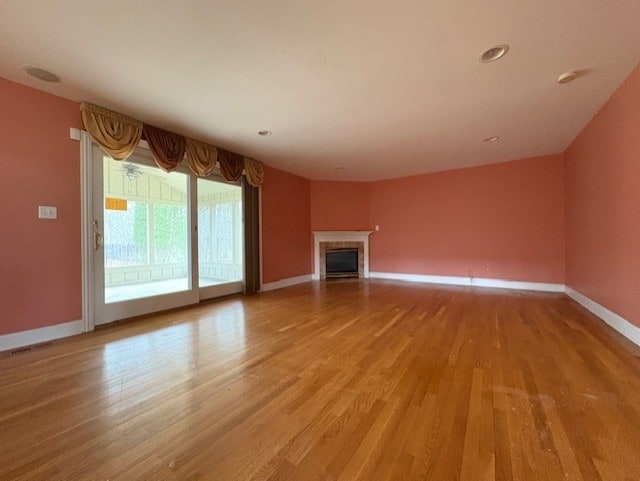 unfurnished living room featuring a fireplace, baseboards, and light wood-style floors