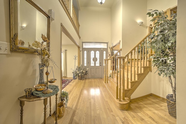 entryway with wood finished floors, a high ceiling, and stairway