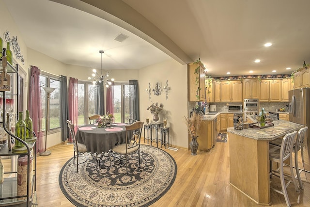 dining space featuring a toaster, baseboards, a notable chandelier, light wood-style floors, and recessed lighting