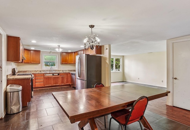 kitchen featuring a sink, a chandelier, appliances with stainless steel finishes, brown cabinetry, and light countertops