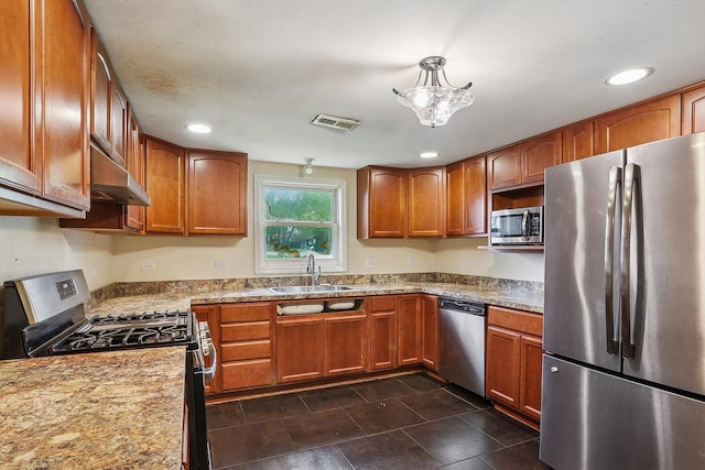 kitchen featuring stainless steel appliances, a sink, under cabinet range hood, brown cabinets, and recessed lighting