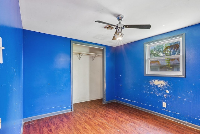 unfurnished bedroom with wood finished floors, baseboards, and a closet