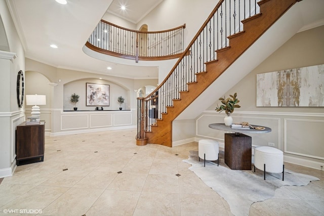 tiled entrance foyer with ornamental molding, a high ceiling, recessed lighting, and stairs